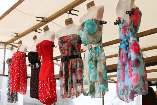 Row of clourfull summerdresses hanging from a market stall
