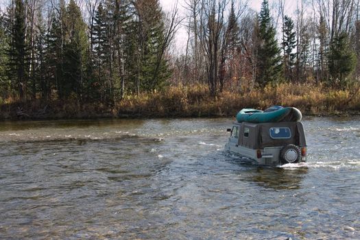 The off-road car forces the river with fast current