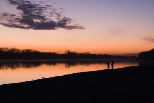 Silhouettes of fishermen on a background of an evening dawn