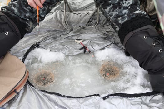 fisherman in a tent on winter fishing