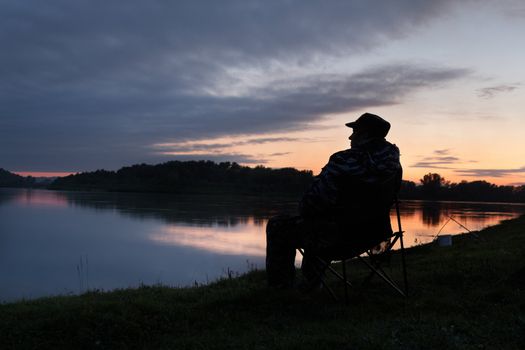 Silhouette of the fisher on a background of an evening dawn