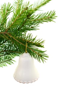 white ceramic bell hangs on green fir branch 