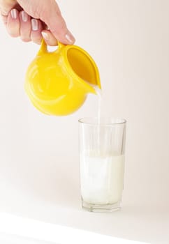  hand tips milk off jug into glass 