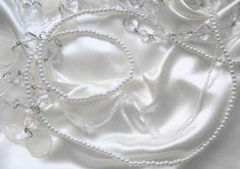 White pearls and nacreous beeds on white silk as wedding background 