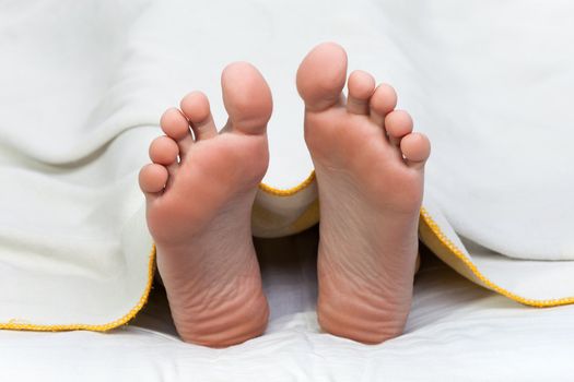 Bed blanket on dead sleeping human body foot toe