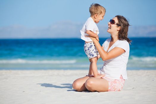 Young mother and her son playing happily at pretty beach