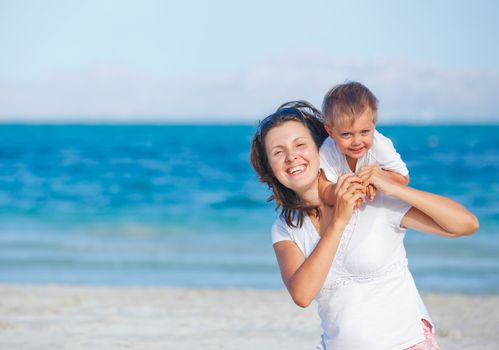 Young mother and her son playing happily at pretty beach