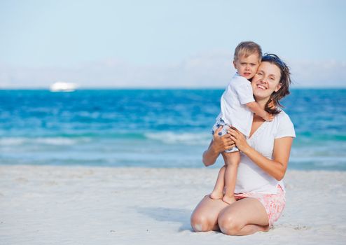 Young mother and her son playing happily at pretty beach