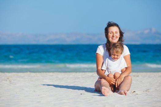 Young mother and her son playing happily at pretty beach