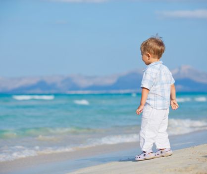 Back view of  little cute boy on the beautiful exotic white beach, Mallorca, Spain