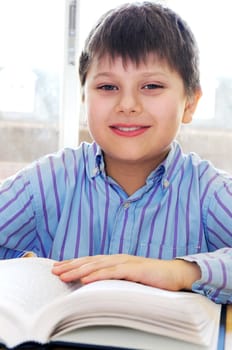 Happy school boy studying with a book