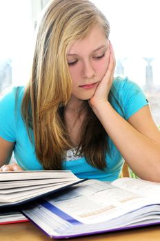 Teenage girl studying with textbooks looking unhappy