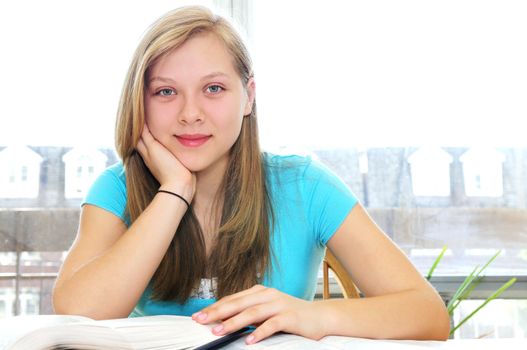 Happy smiling teenage girl studying with textbooks