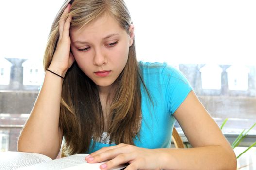 Teenage girl studying with textbooks looking unhappy