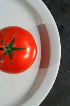 Close up of a red tomato on a plate.
