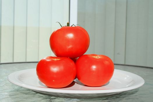 Close up of the red tomatos on a plate.
