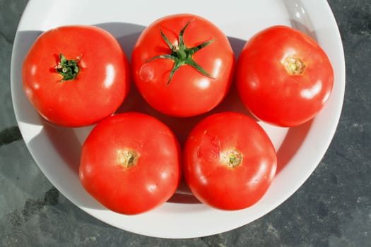 Close up of the red tomatos on a plate.
