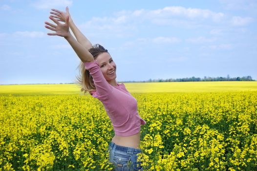 Joyful girl among blooming rape field