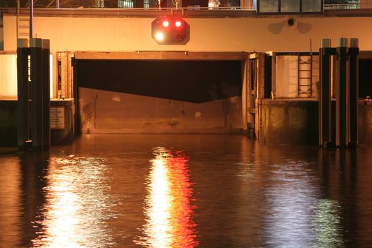 Night shot of closed lock gate at a canal in the city center of Hamburg, Germany. The traffic lights reflect in the water surface (exposureTime: 3.2 seconds). This canal connects the Elbe river and the Alster lake.