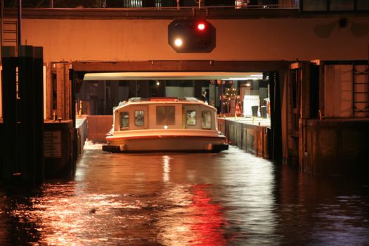 Night shot of a passenger ship driving into a lock gate on a canal in the city center of Hamburg, Germany. This canal connects the Alster lake and the Elbe river.