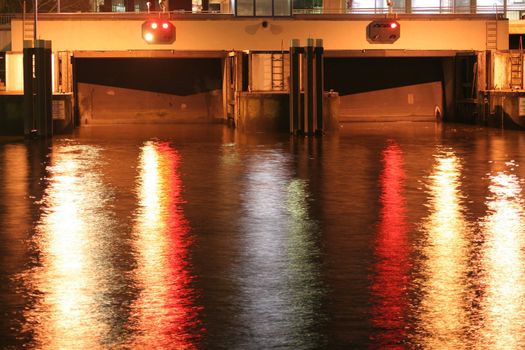 Night shot of two closed lock gates at a canal in the city center of Hamburg, Germany. The traffic lights reflect in the water surface (exposureTime: 3.2 seconds). This canal connects the Elbe river and the Alster lake.