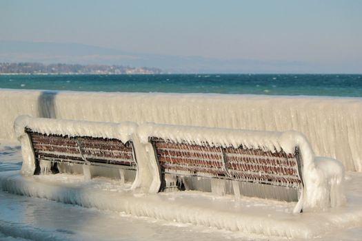 Two frozen benches because of cold winter temperature and waves at Versoix, Switzerland