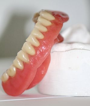 Lower denture (prothesis) upon plaster in white dental laboratory background