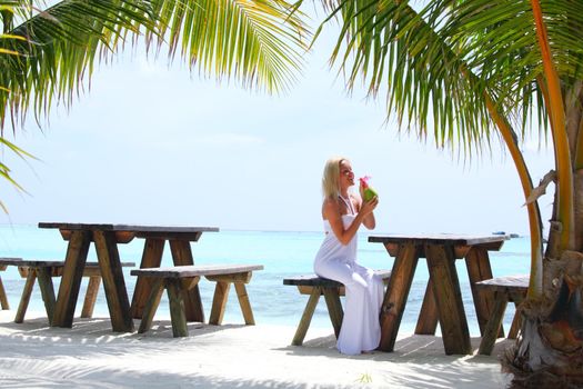 woman sitting in a tropical cafe on the background of a  palm trees and sky and sea