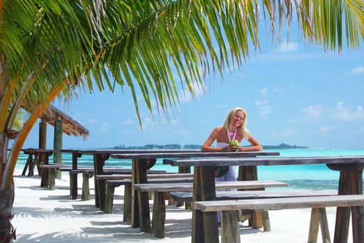 woman sitting in a tropical cafe on the background of a  palm trees and sky and sea