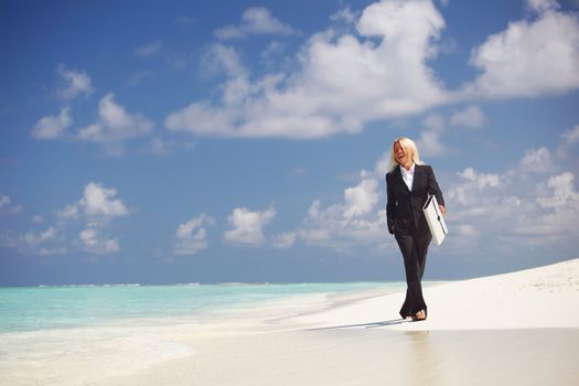 business woman with briefcase walking on the desolate ocean coast