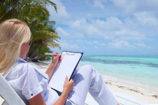 business woman with blank paper lying on a chaise lounge in the tropical ocean coast