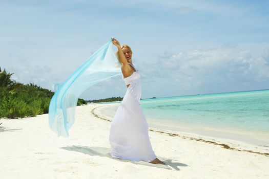 woman with a white fabric in his hands on the beach