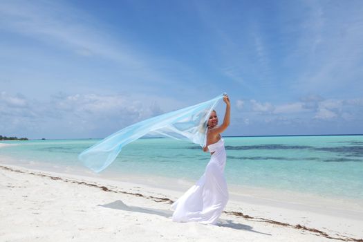 woman with a white fabric in his hands on the beach