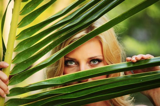 woman hiding behind the palm leaves