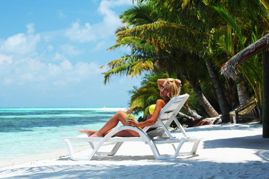 tropical woman on lounge with a coconut cocktail