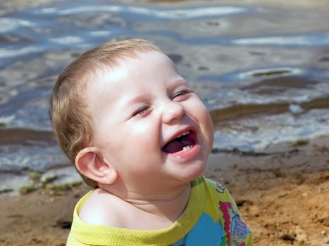 Little child smiling on water beach at summer