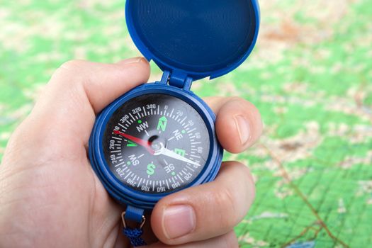 Hand holding travel north direction compass on map