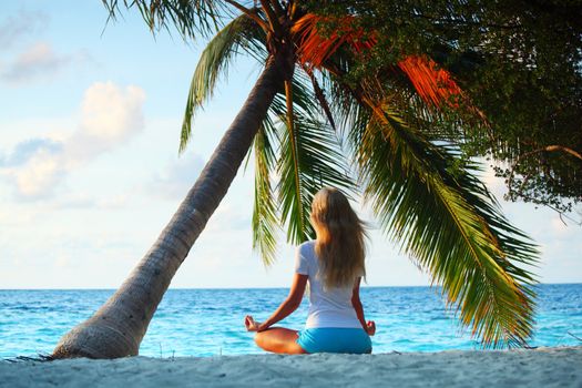 yoga woman on sea coast under palm