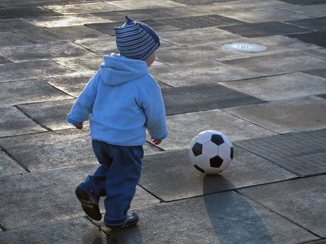 Little child playing soccer ball outdoors