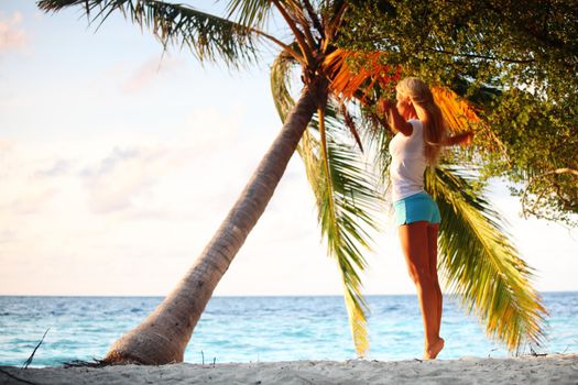 yoga woman on sea coast under palm