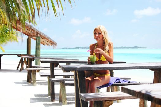 woman sitting in a tropical cafe on the background of a  palm trees and sky and sea