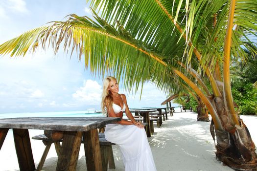 woman sitting in a tropical cafe on the background of a  palm trees and sky and sea