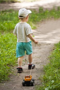 Little child boy playing car toy rope towing game