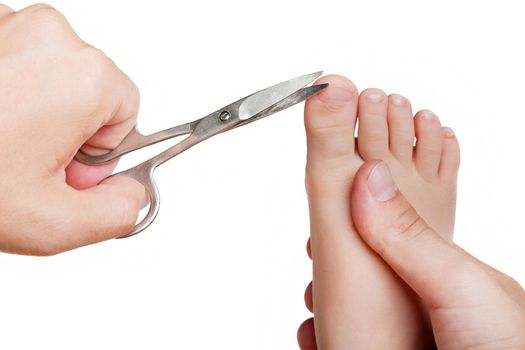 Human hand holding scissors trimming child toenail