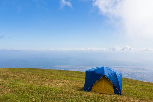 Tent on a grass under white clouds and blue sky