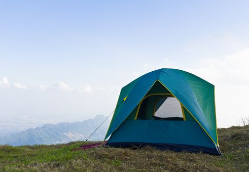 Tent on a grass under white clouds and blue sky