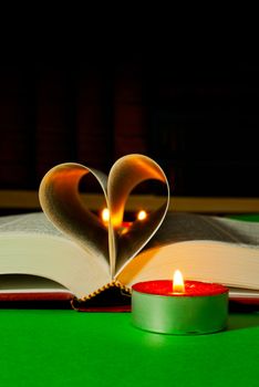 Open book laying on the table with burning candle