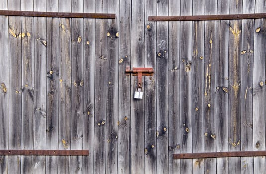 Old wooden farm rural building doors locked with padlock. Background of old architecture.