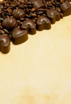 Heart shaped chocolate candies and coffee beans on grungy paper