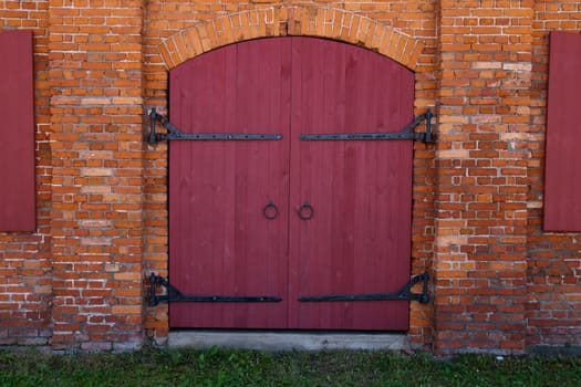 Old Red wooden door in red brick wall 